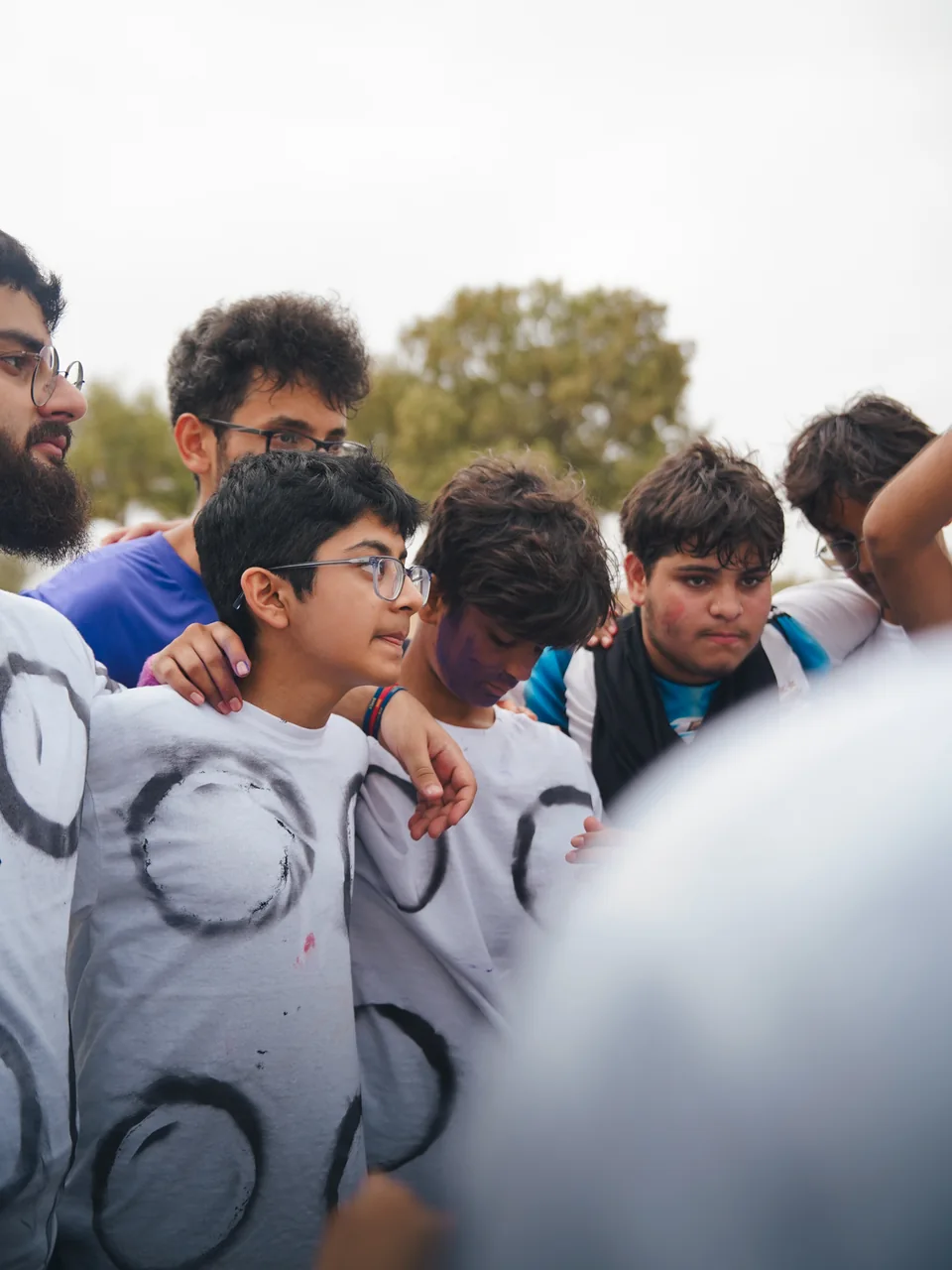 Ground Zero teammates shoulder to shoulder in an outdoor huddle.